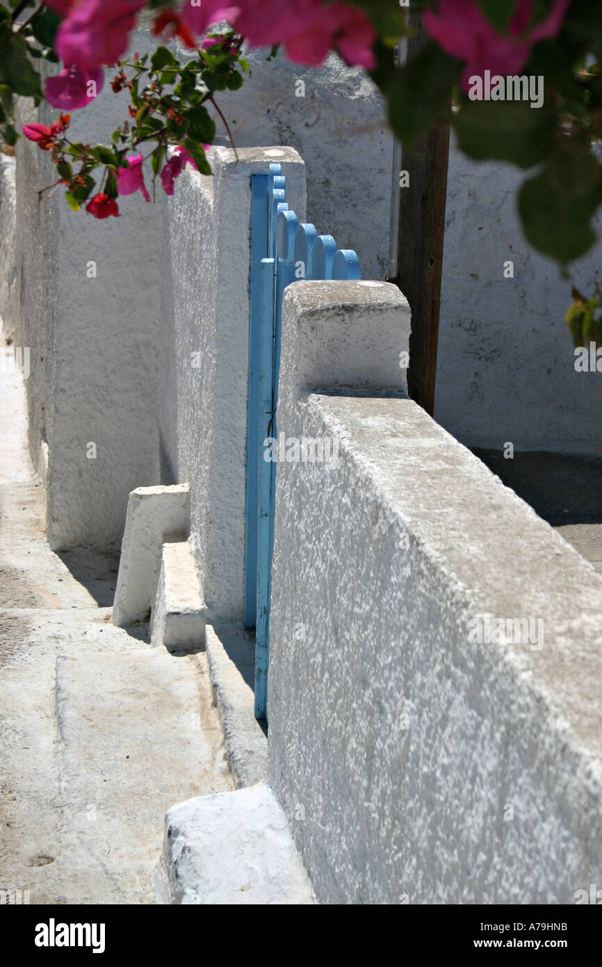 Blue Gate and Flowers: A blue gate set in white washed walls surrounded by the bright flowers of a garden Stock Photo