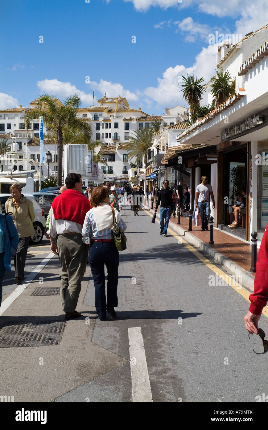 dh Marbella Harbour PUERTO BANUS SPAIN Couple walk along harbour road waterfront quayside street holiday costa del sol tourist walking seafront Stock Photo