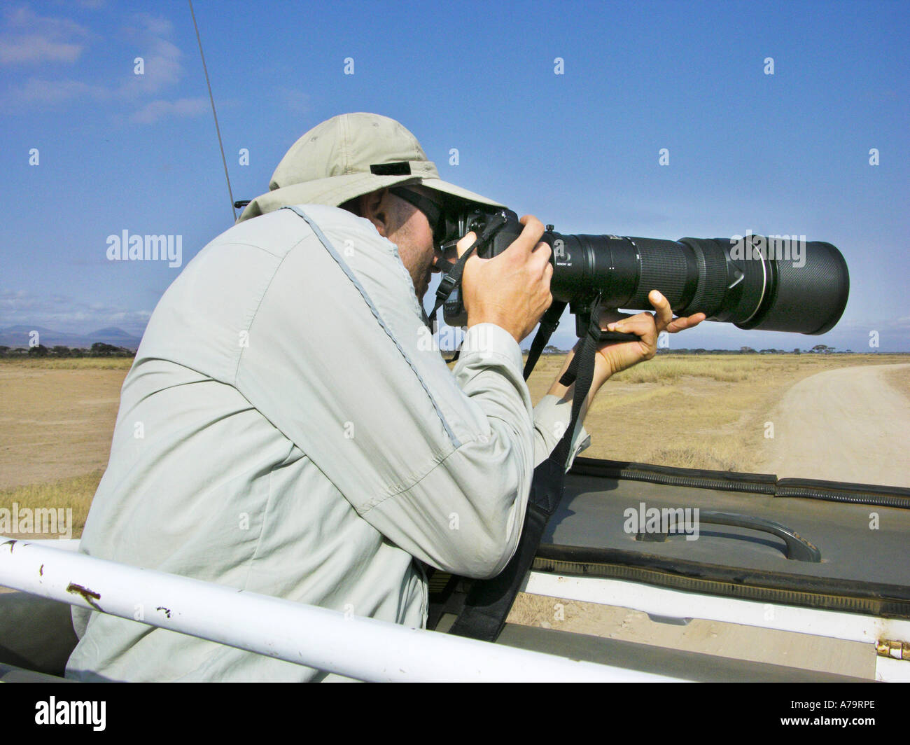 Fotograf man photographer at work with huge tele lens telephoto on jeep SAFARI Kenya   KENIA East  Africa AMBOSELI nationalpark Stock Photo