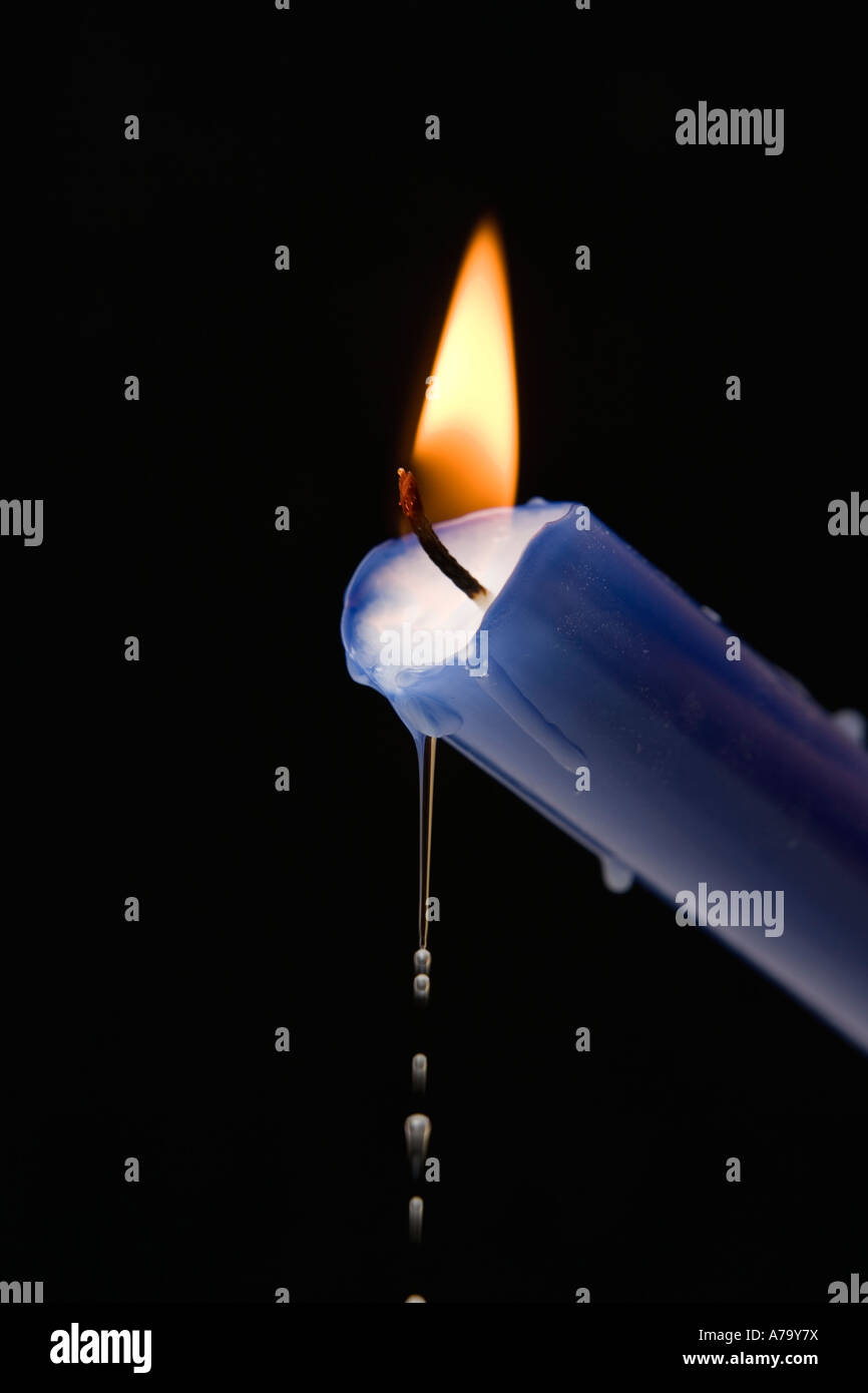 Hot liquid wax dripping from a burning blue candle Stock Photo