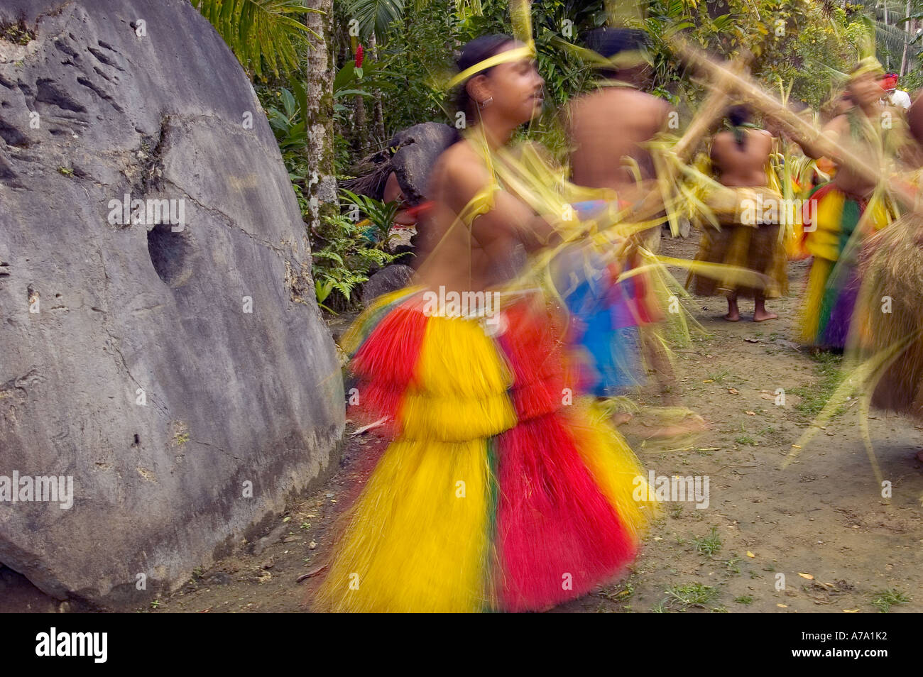 Motion blur of Yapese traditional dancers performing Stick Dance in front of Stone Money Yap Micronesia Pacific Ocean Stock Photo