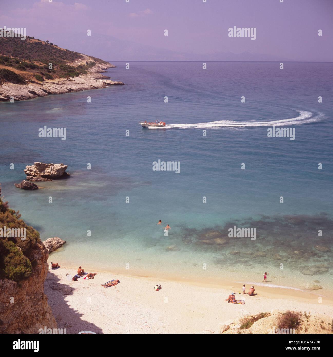 View from cliff top as tourist speed boat leaves white wake in Zingu