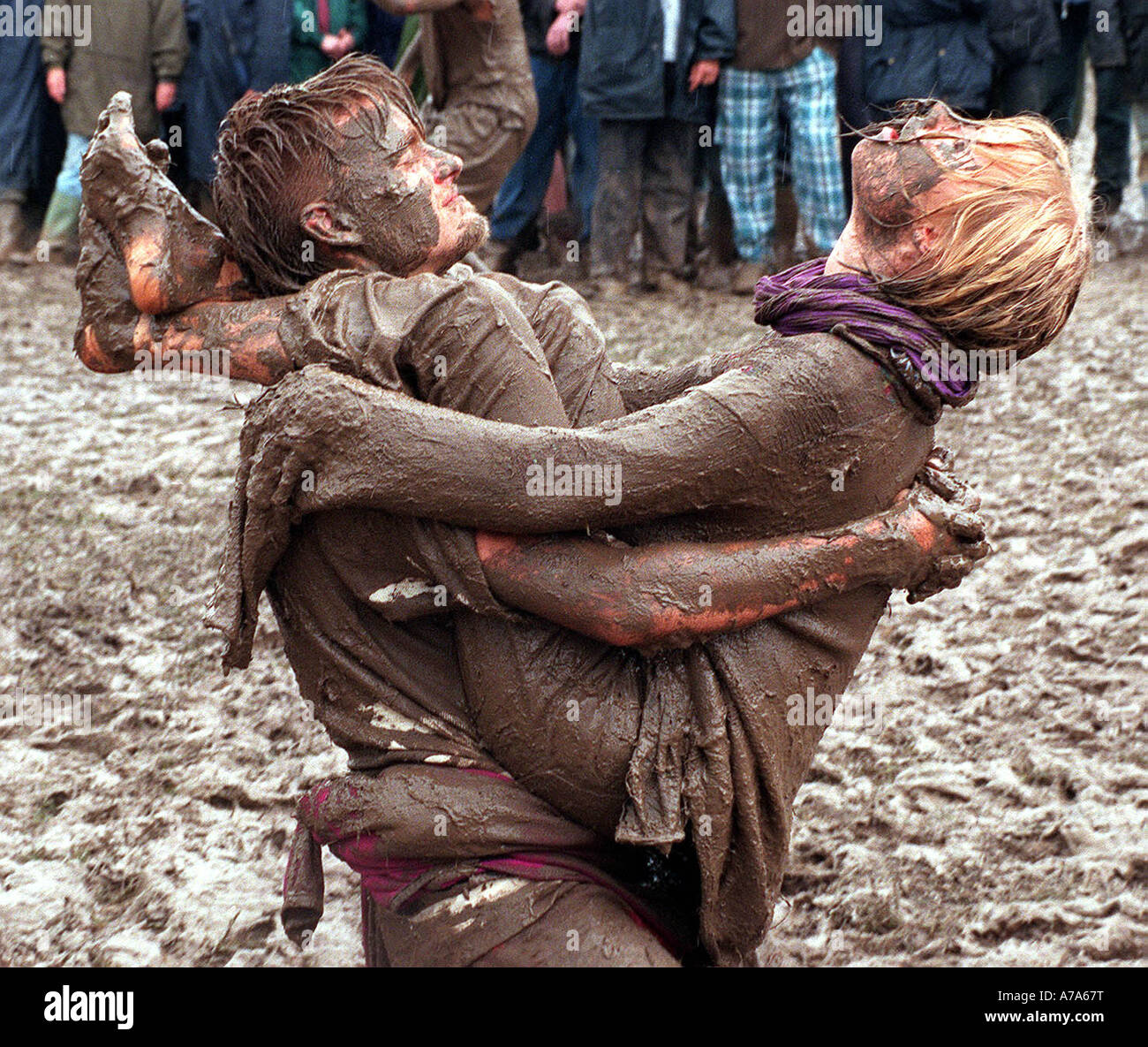Mud wrestling weather. A couple embrace in the mud at a wet and soggy Glastonbury music festival. Stock Photo