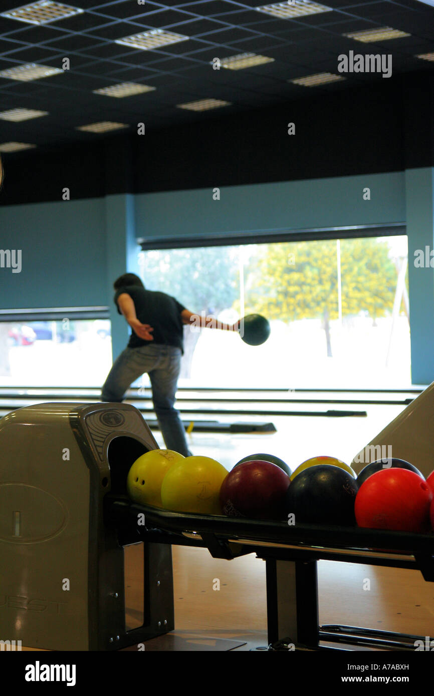Bowling balls and young man playing bowls in the background Stock Photo