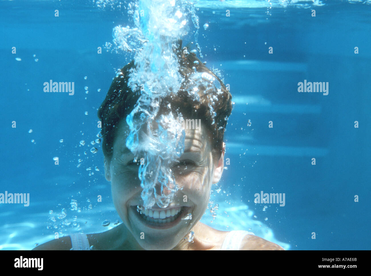 smiling girl underwater blowing bubbles in a swimming pool Stock Photo