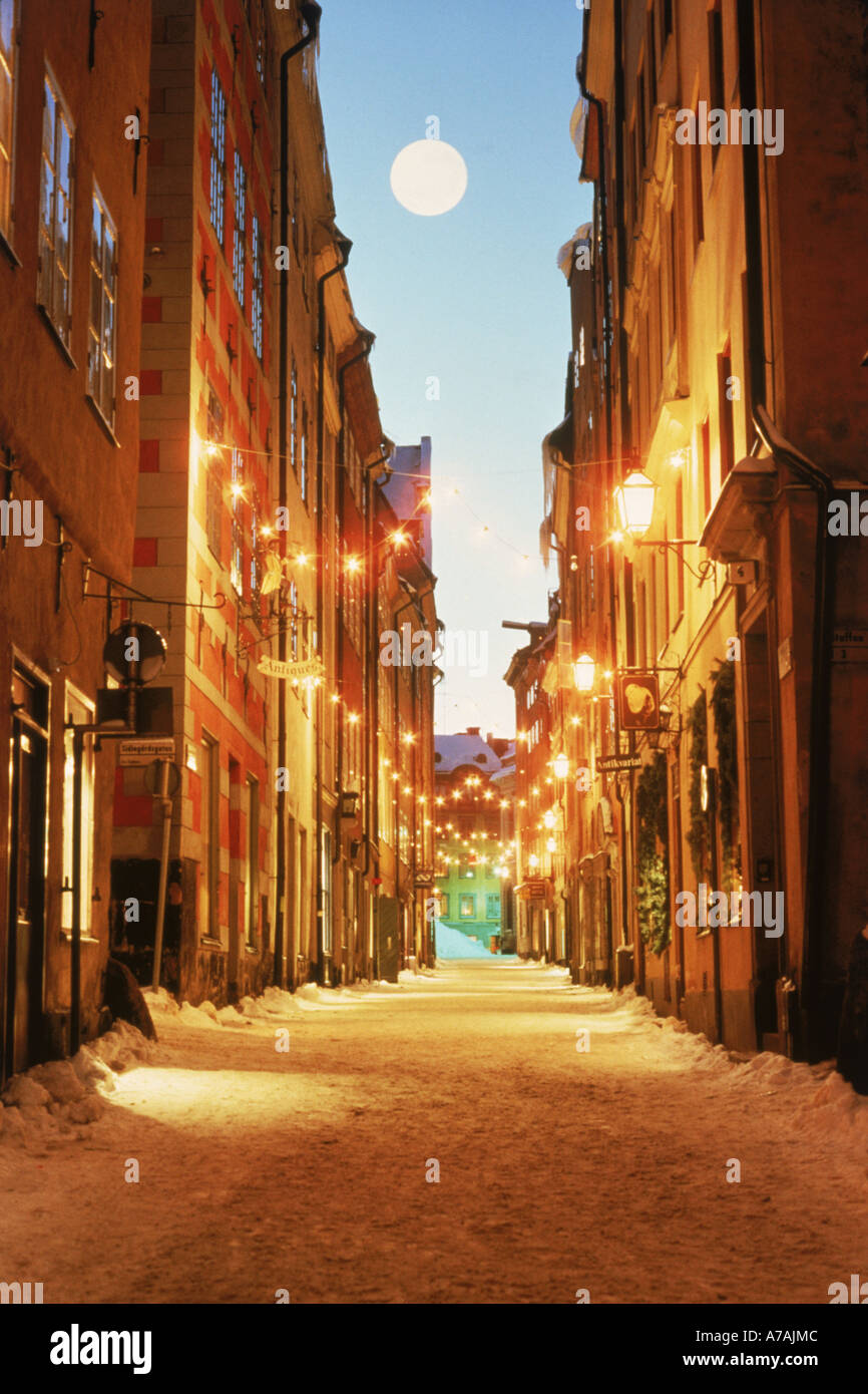 Full moon over snow on Svartmangatan with Christmas decorations in the Stockholm Old Town or Gamla Stan Stock Photo