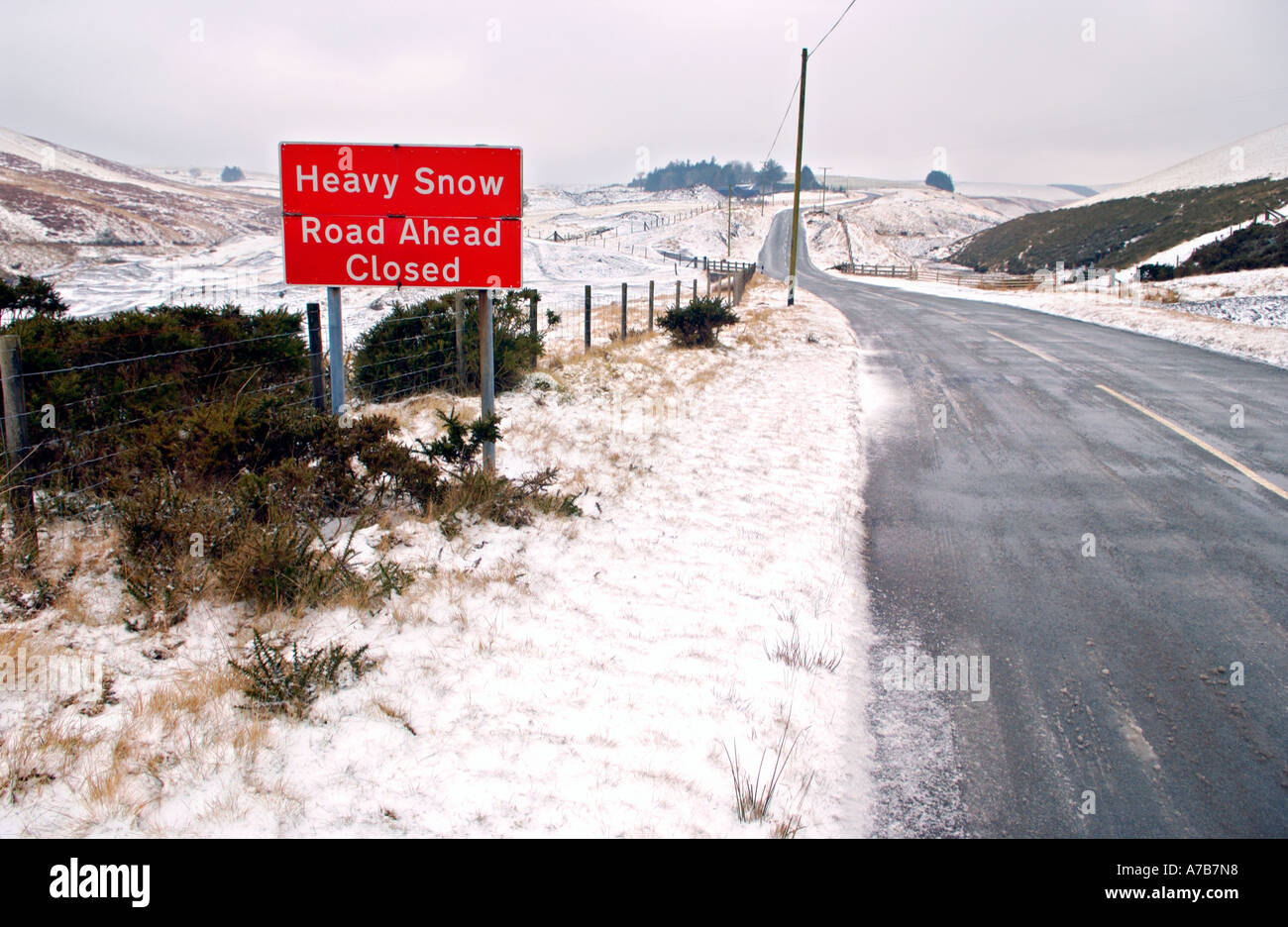 HEAVY SNOW ROAD AHEAD CLOSED sign on mountain road between Llanidloes