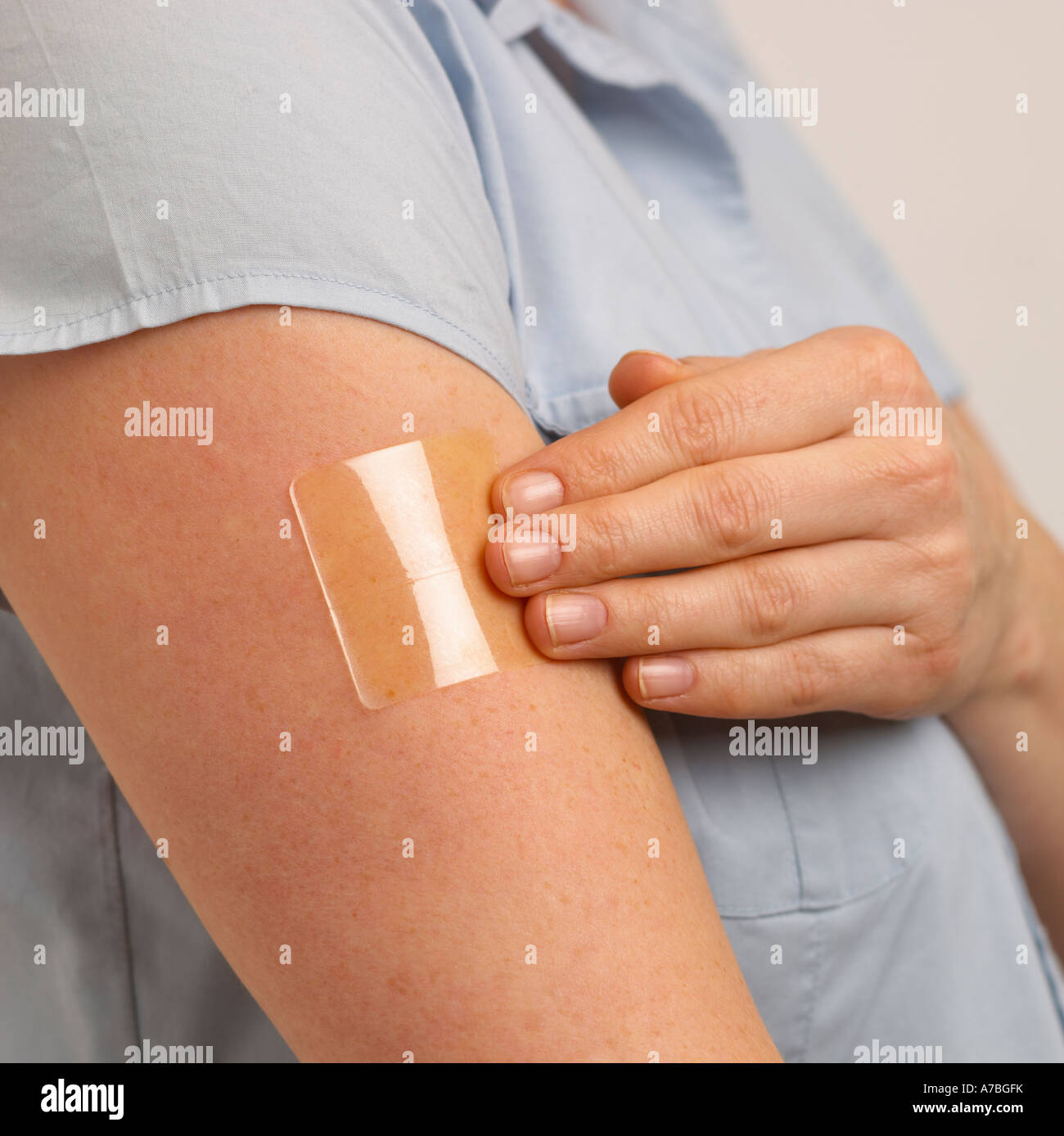 ATTRACTIVE HEALTHY YOUNG BLOND WOMAN APPLYING TRANSPARENT NICOTINE PATCH TO ARM Stock Photo