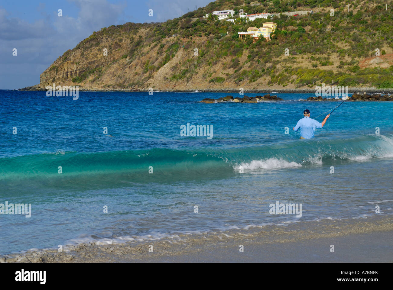 Man waist deep in ocean waves fly fishing in St Maarten on Caribbean