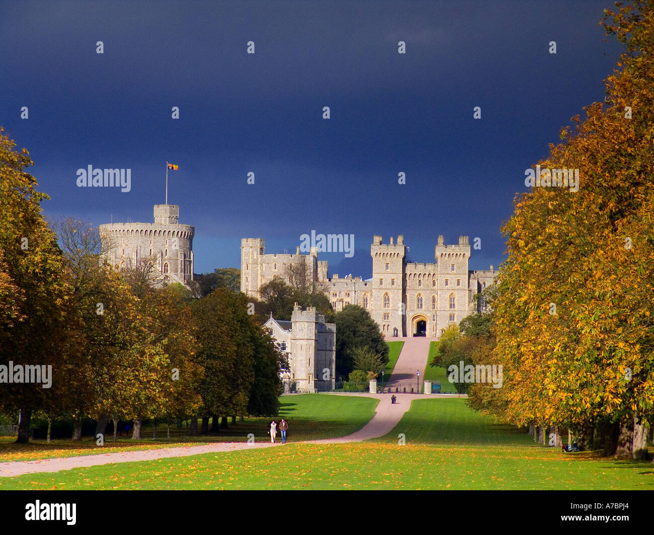 Windsor Castle flying Royal Standard viewed down the Long Walk with walkers, lit by dramatic sunlight in autumn  Berkshire UK Stock Photo