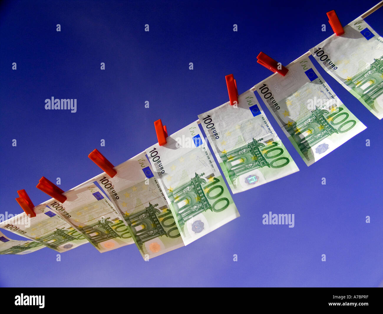 EUROS NOTES 100’s CONCEPT BLUE SKY Crisp new Euro notes pegged flying high in a line against a sunny blue sky Stock Photo