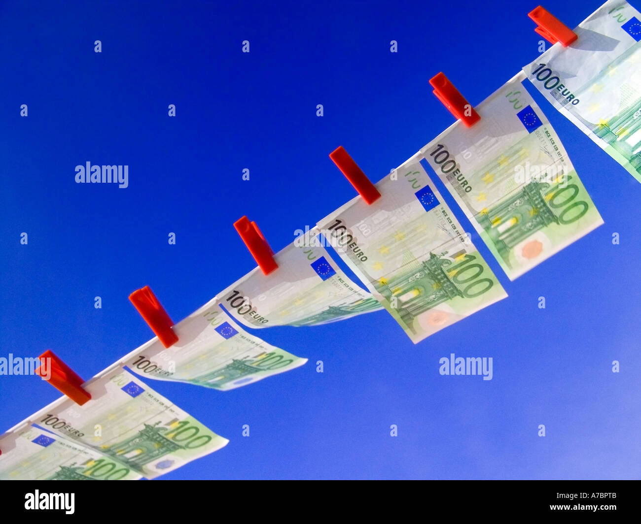 EURO NOTES WASHING LINE Crisp new 100 Euro notes fluttering flying high in the breeze pegged in a line against a sunny blue sky Horizontal Landscape Stock Photo