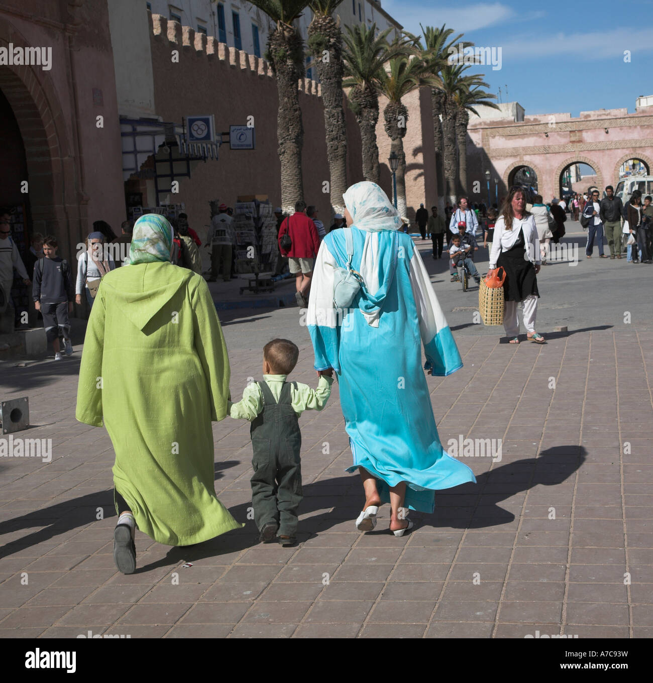 Two women holding a toddlers hands walking in the street Essaouira