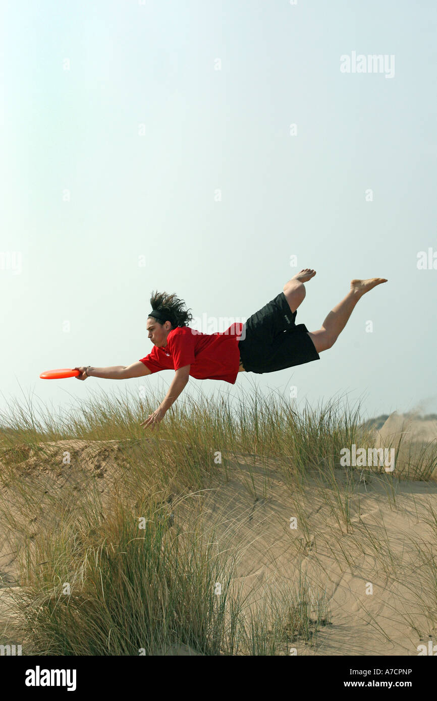 man in mid air takes part in extreme sport of ultimate frisbee at Balmedie beach, Aberdeen, Aberdeenshire, UK. Stock Photo