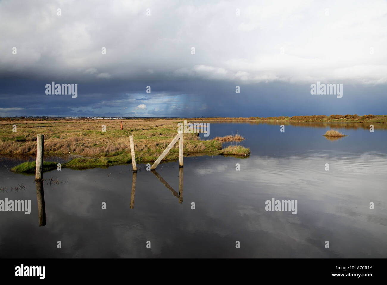 Fence posts reflected in Lymington Salt Marsh water on a stormy day in