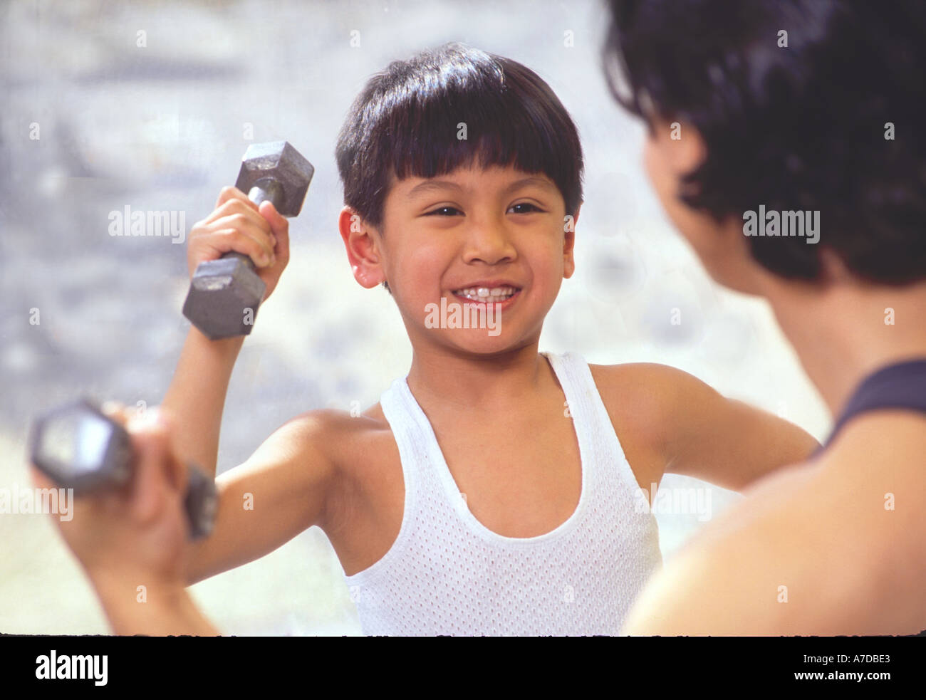 Asian American boy exercising with weights with father Stock Photo