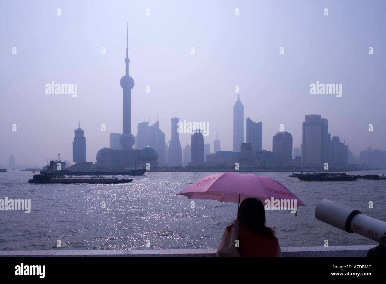 Asia China Shanghai Young woman looking across Huangpu River at Oriental TV Tower and and skyscrapers of Pudong skyline Stock Photo