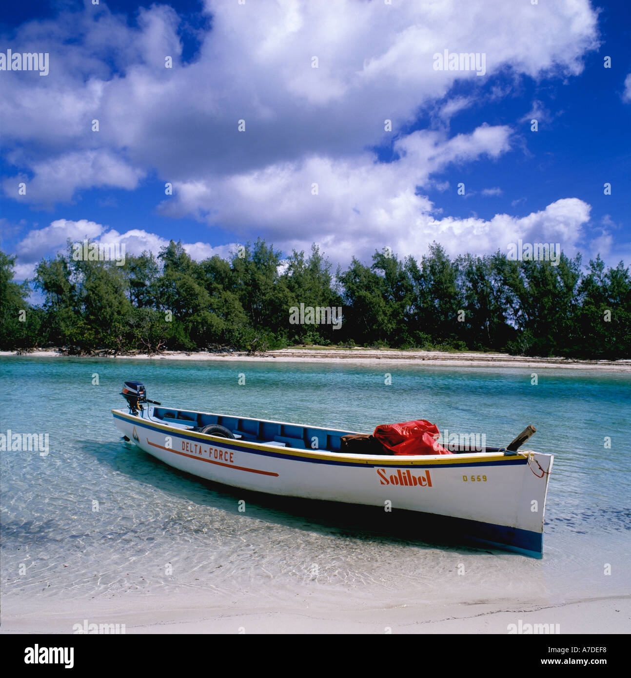 Ile aux Cerfs Mauritius, Indian Ocean, with open wooden boat in foreground and island with casuarina trees and deserted beach behind Stock Photo