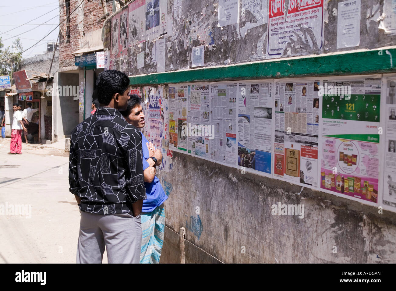 Men reading a newspaper that is posted daily for the public to read for free in Dhaka Bangladesh Stock Photo