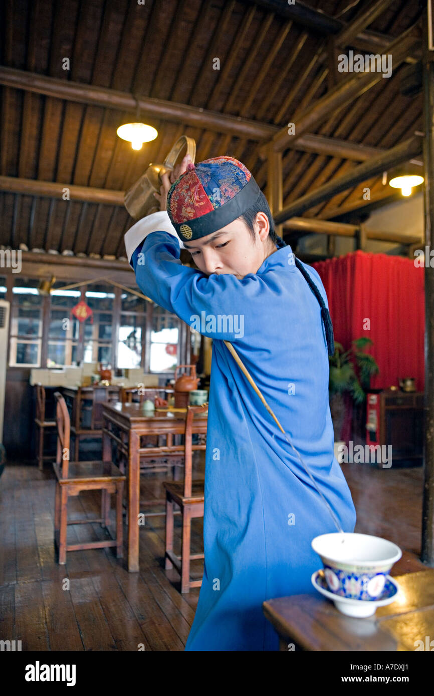 CHINA HANGZHOU Young tea server pours tea from behind his back using  antique long spout teapot Stock Photo - Alamy