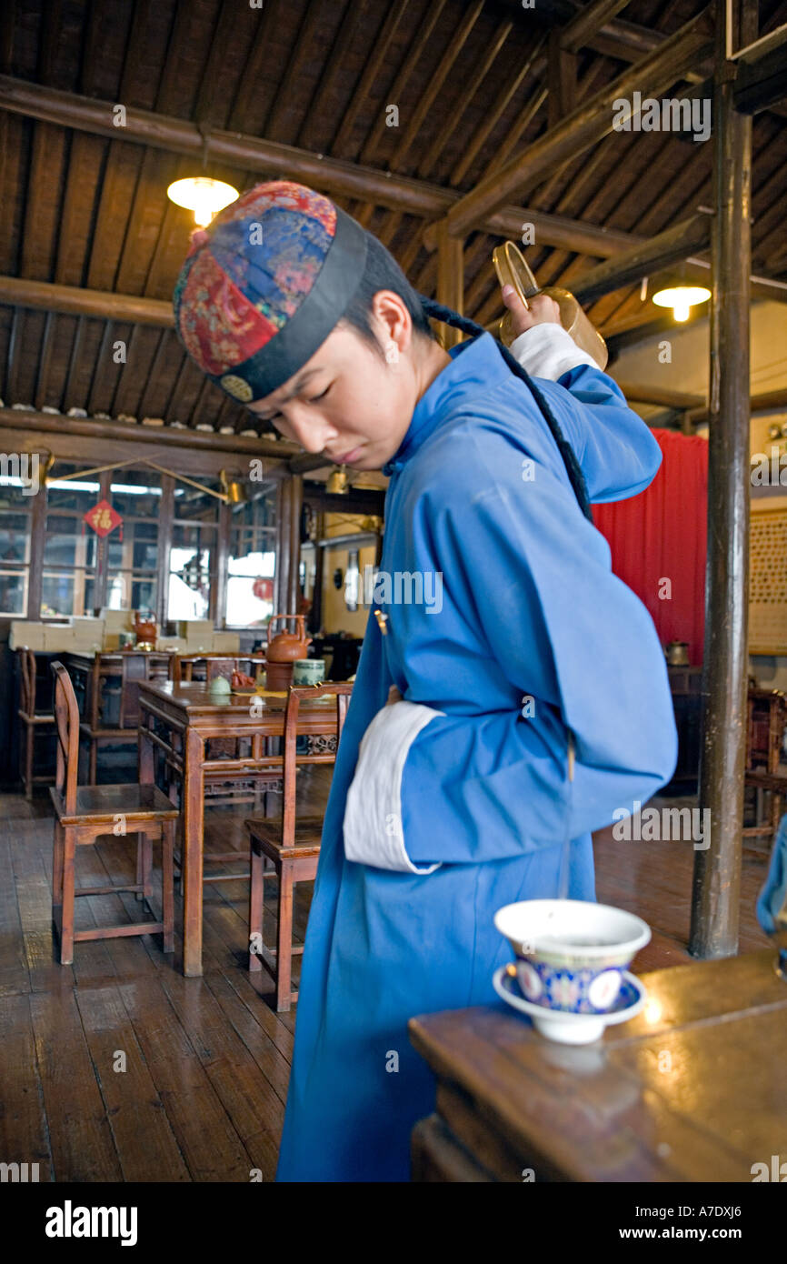 CHINA HANGZHOU Young tea server pours tea from behind his back using  antique long spout teapot Stock Photo - Alamy