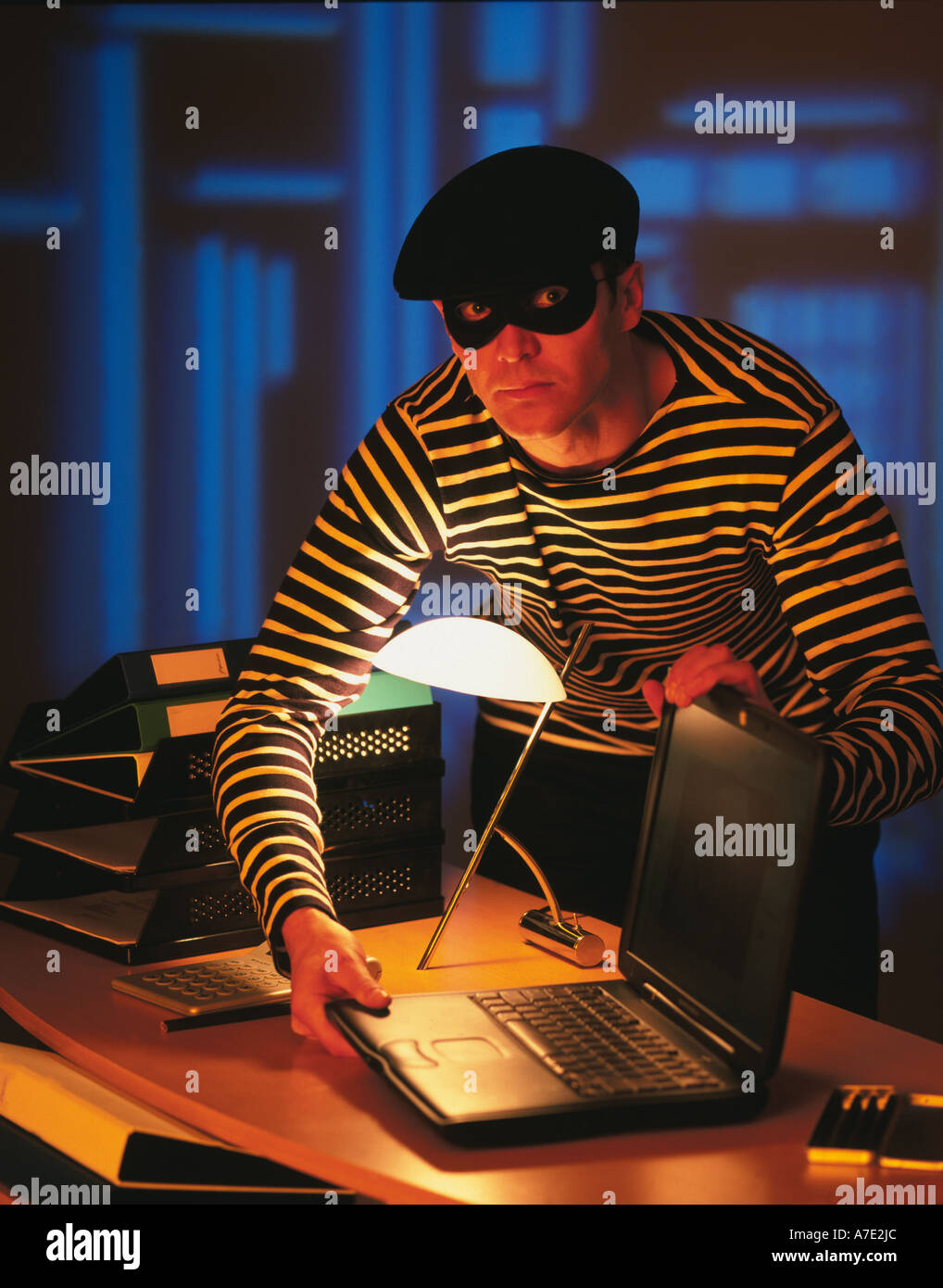 Burglar in traditional costume,Thief stealing a laptop computer Stock Photo