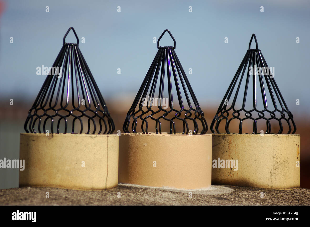 Three chimney pots with cowls to protect them from birds on a rooftop