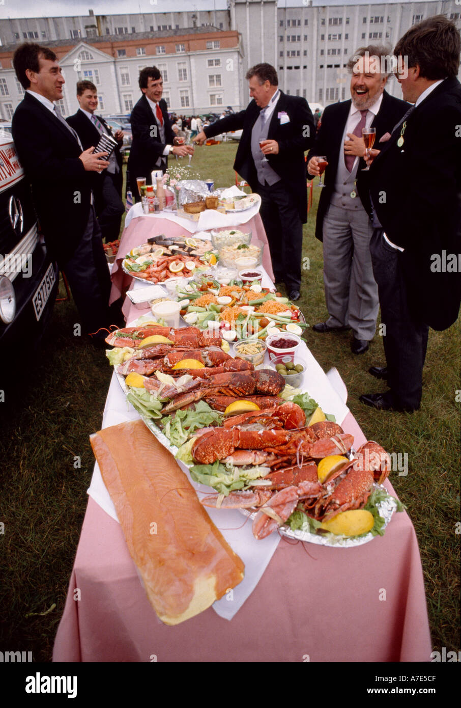 A group of men enjoy an open air meal in the car park at Epsom racecourse on Derby Day Epsom surrey England Stock Photo