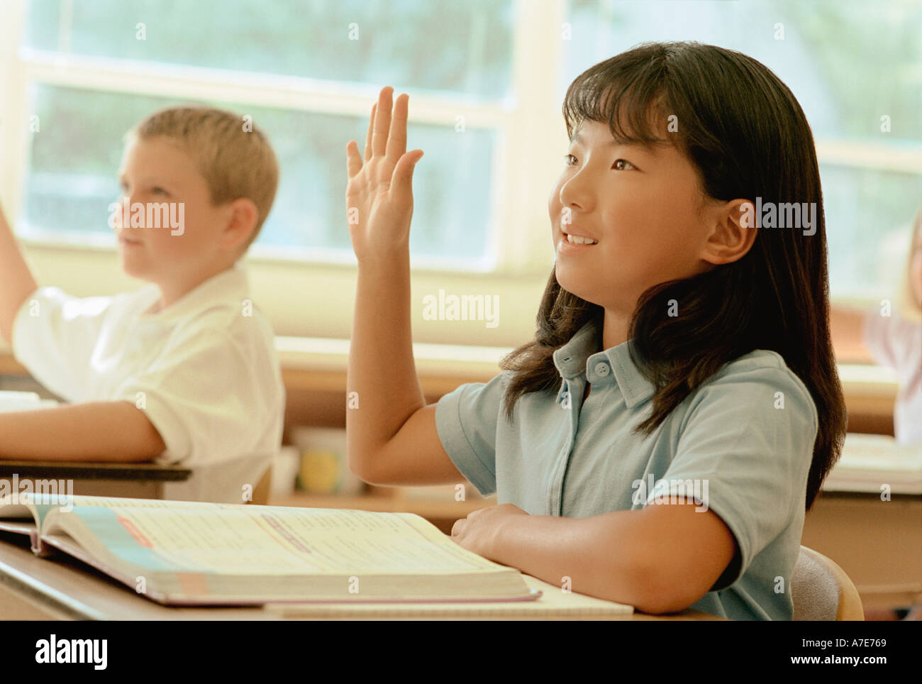 Eager school children raising their hands in class Stock Photo