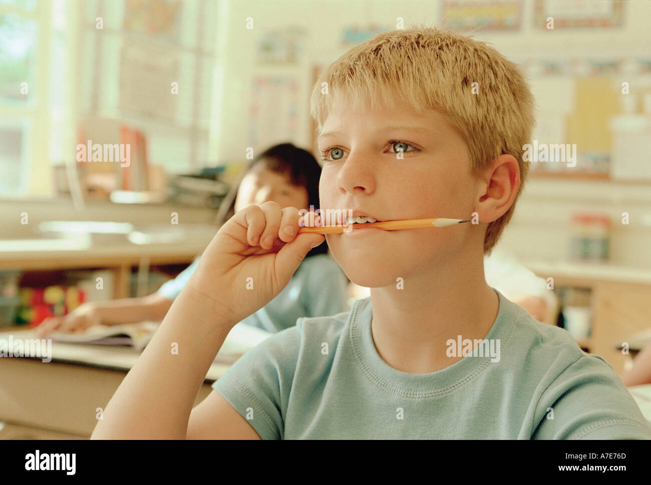 Boy chewing pencil in school classroom Stock Photo