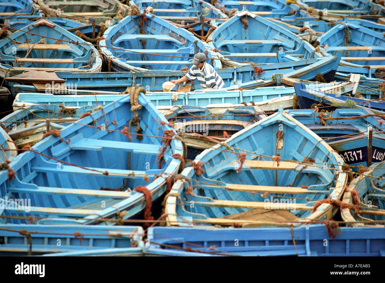 Close up of boy bailing out a boat in the fishing harbour of Essaouira in Morocco in North Africa Stock Photo