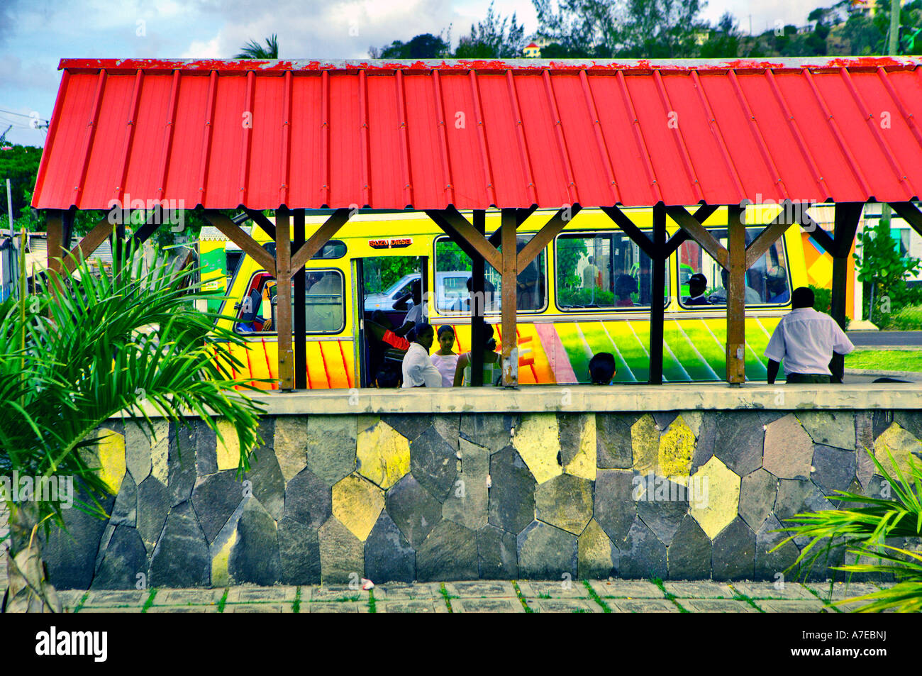 Red roofed Bus shelter with yellow bus in central Port Mathurin, Rodrigues Stock Photo
