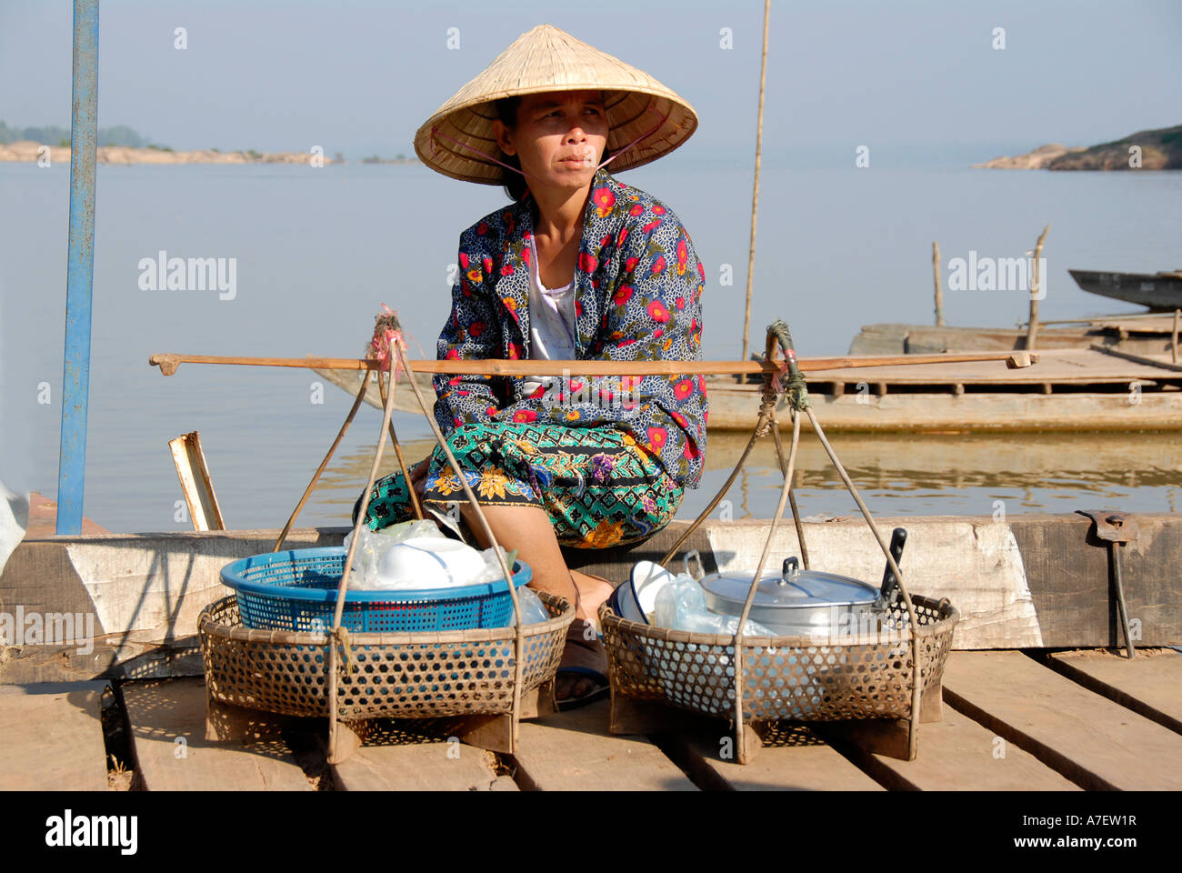 Food seller wearing a rice hat at the riverbanks of Mekong River Champasak Laos Stock Photo