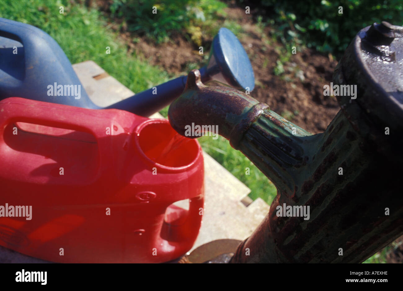 Drawing water from a pump at an allotment on a hot sunny day Stock Photo