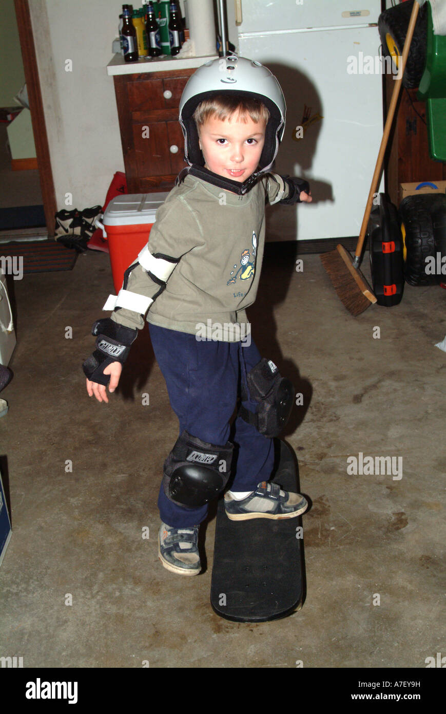 Five year old boy poses with skateboard wearing safety equipment Stock