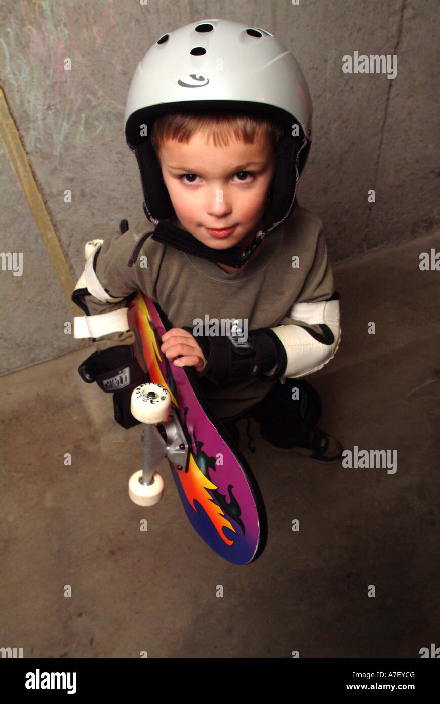 Five year old boy poses with skateboard wearing safety equipment Stock
