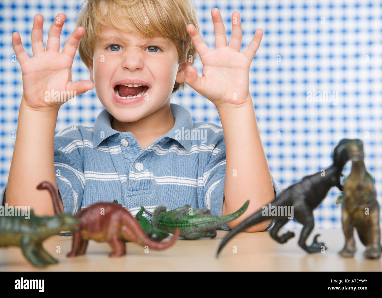 Young boy making face with toy dinosaurs Stock Photo