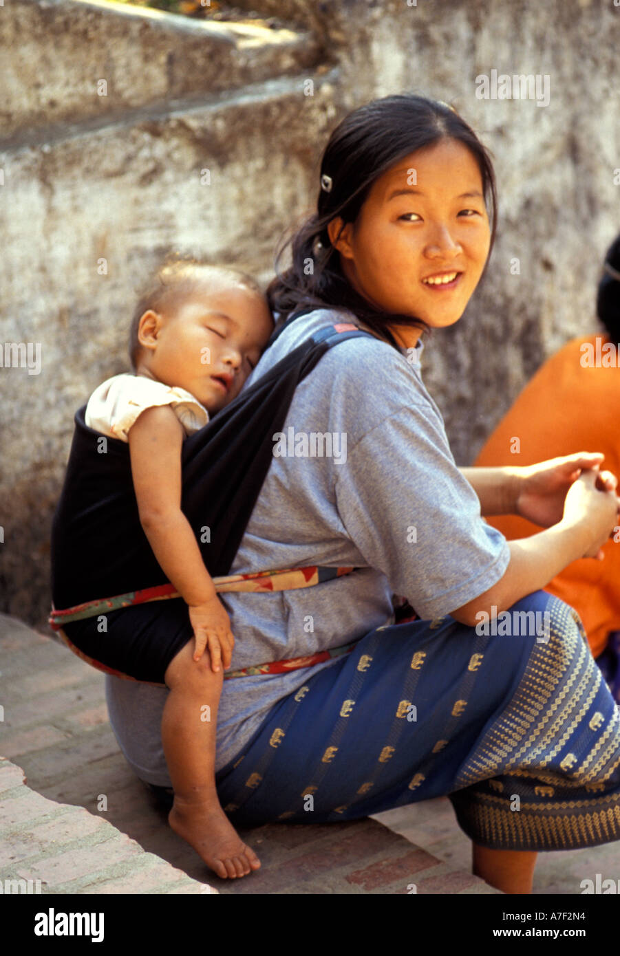 Mother carrying sleeping child on back, Luang Prabang, Laos Stock Photo