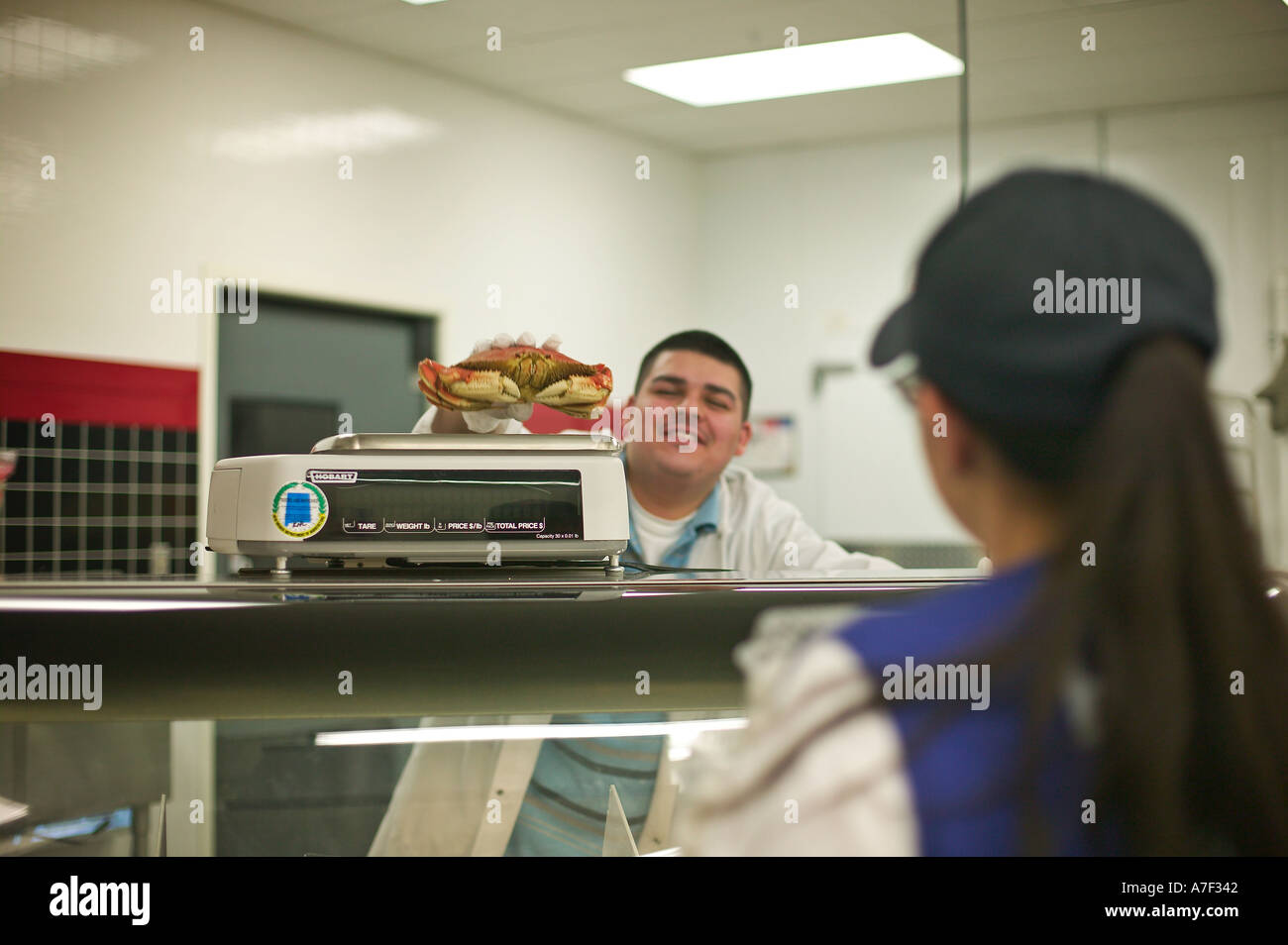 Clerk in seafood department weighs crab for customer at WalMart in