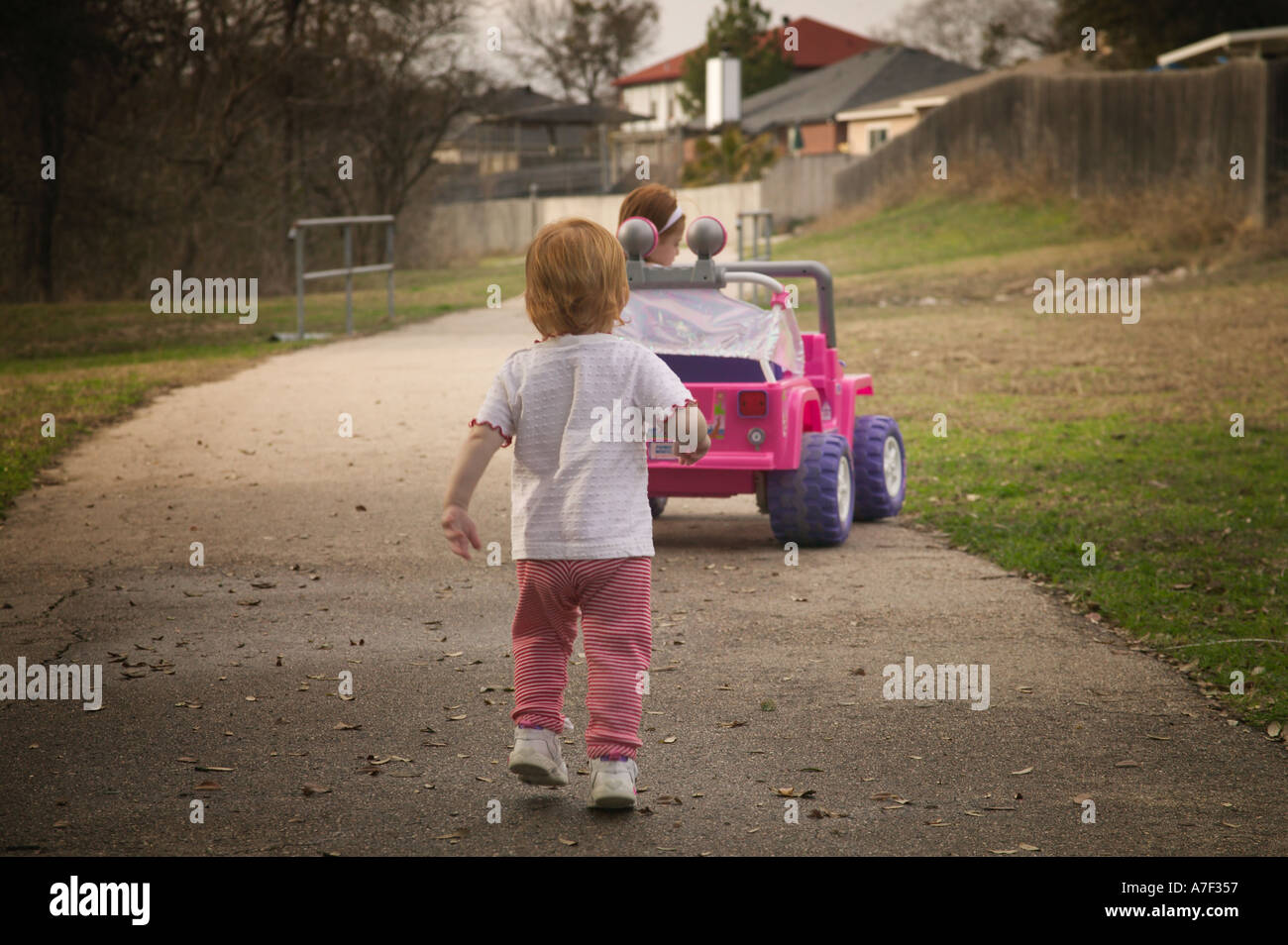 Four Year Old Driving Pink Barbie Jeep With Little Sister Running Behind Stock Photo - Alamy