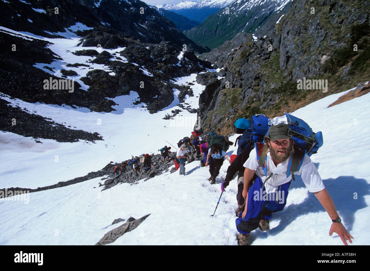 USA Alaska Line of hikers climb snow covered slope to summit of Chilkoot Pass during Dyea to Dawson Race Stock Photo