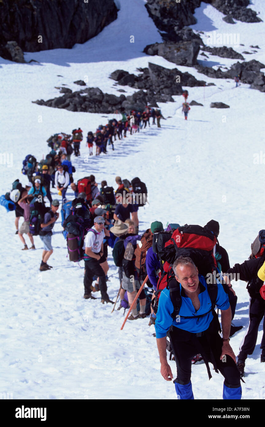 USA Alaska Line of hikers rest during climb up snow covered slope to summit of Chilkoot Pass during Dyea to Dawson Race Stock Photo
