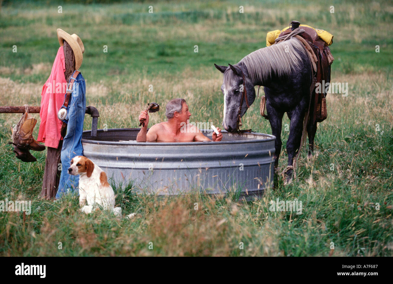 Cowboy bathing  outdoors in a water tank Stock Photo