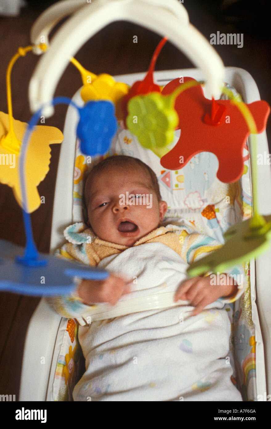 Detroit Michigan A newborn infant yawns while studying a mobile hanging above her Stock Photo
