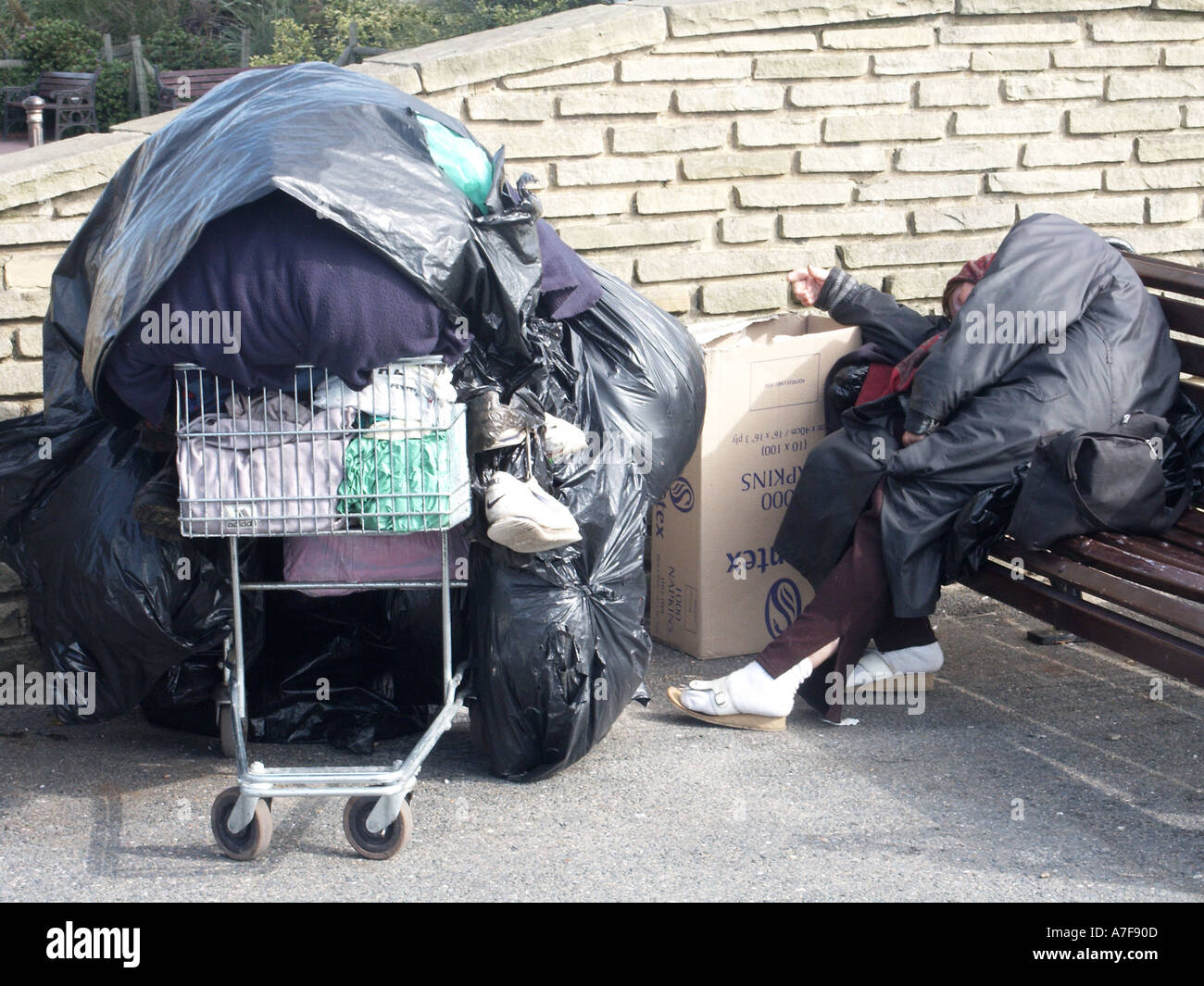 A person sleeping rough on seafront promenade belongings in a supermarket trolley Worthing West Sussex England UK Stock Photo