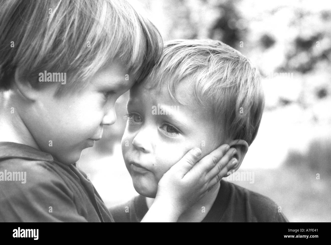 Older sister caresses and comforts scared younger brother Stock Photo