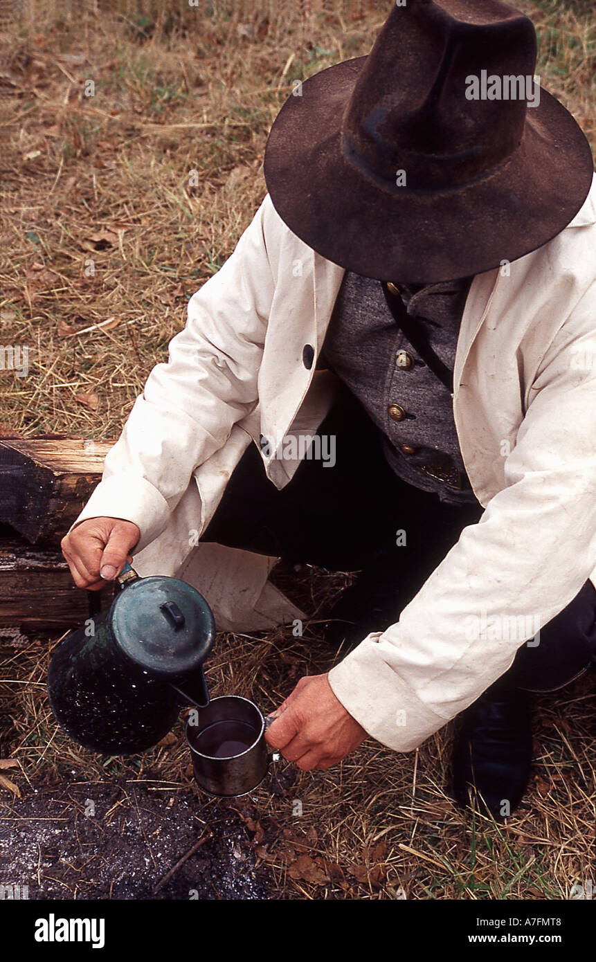 Confederate soldier leaning over a campfire filling his coffee cup Stock Photo
