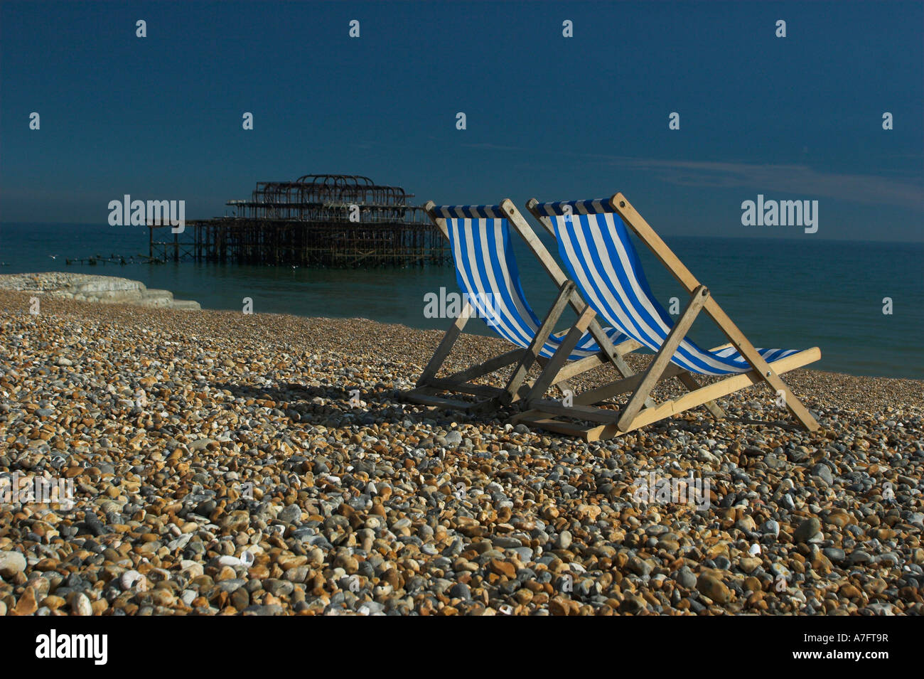 TWO BLUE AND WHITE STRIPED DECK CHAIRS on Brighton Beach next to the ...