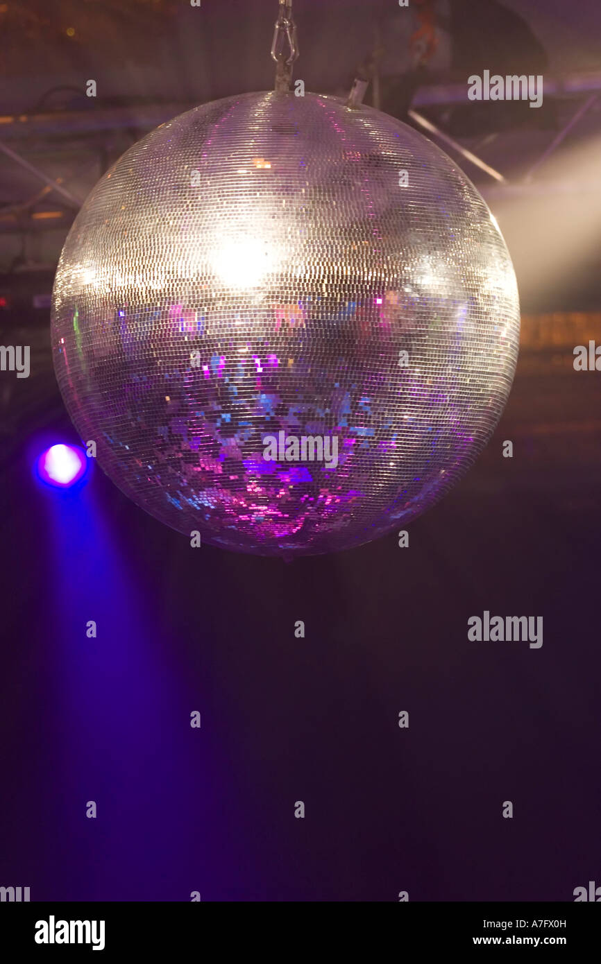 A huge mirrored glitter ball illuminated by colored lights Stock Photo