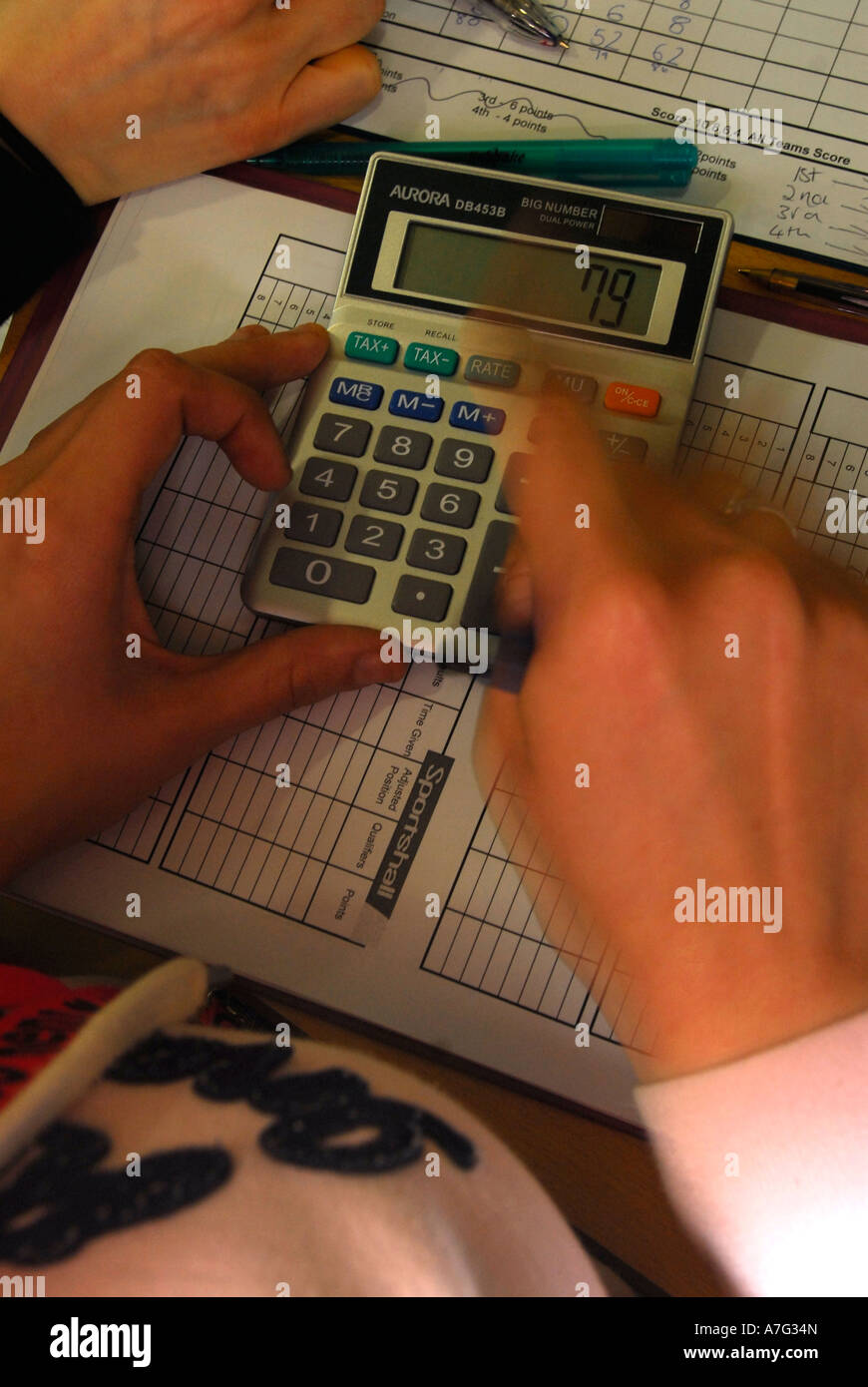 Woman using calculator at a school sports event London UK Stock Photo